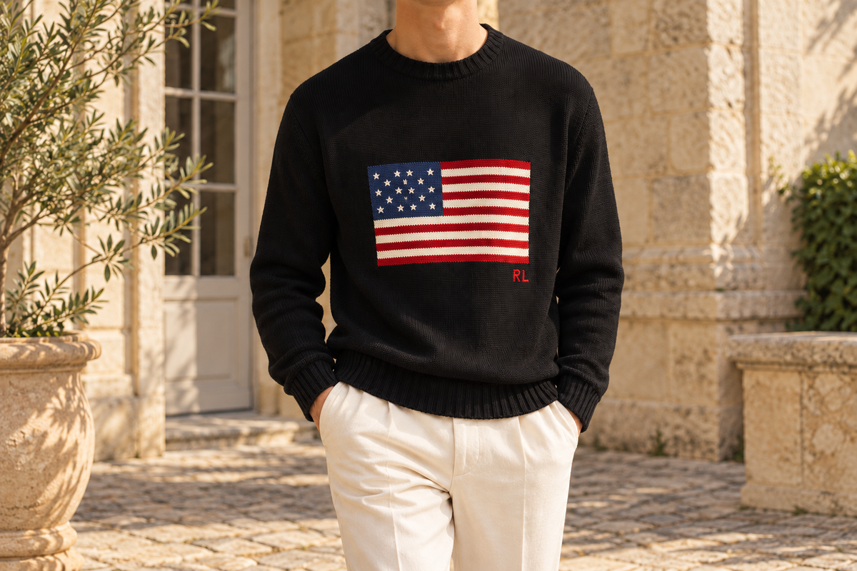 Pull noir à motif drapeau et pantalon ivoire dans une cour en pierre